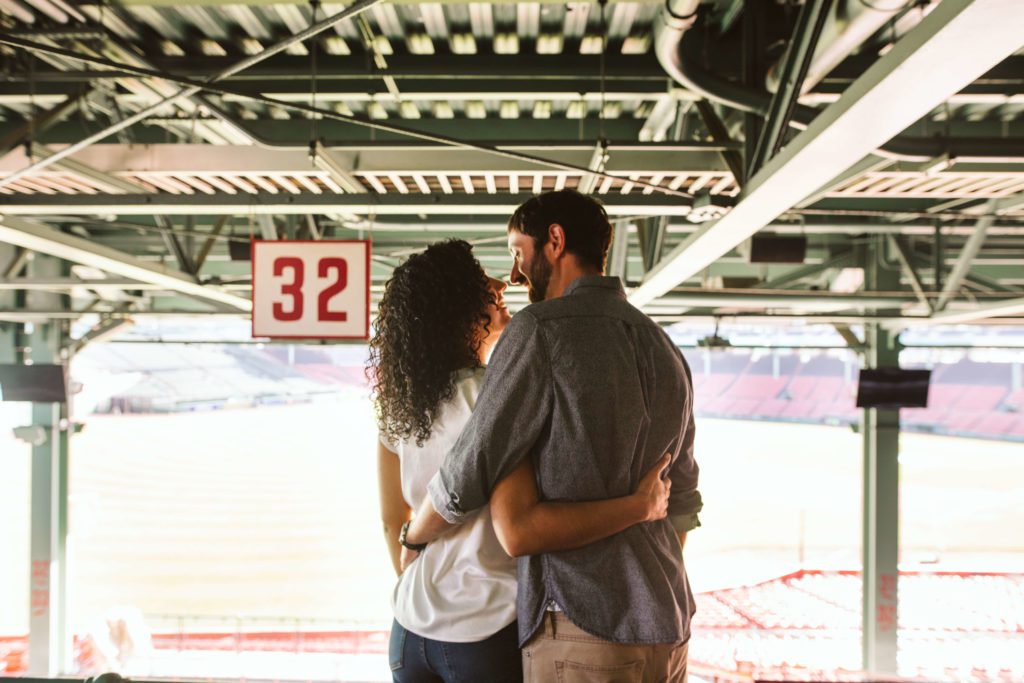 Couple posing in the stands at Fenway Park during their Boston engagement photos